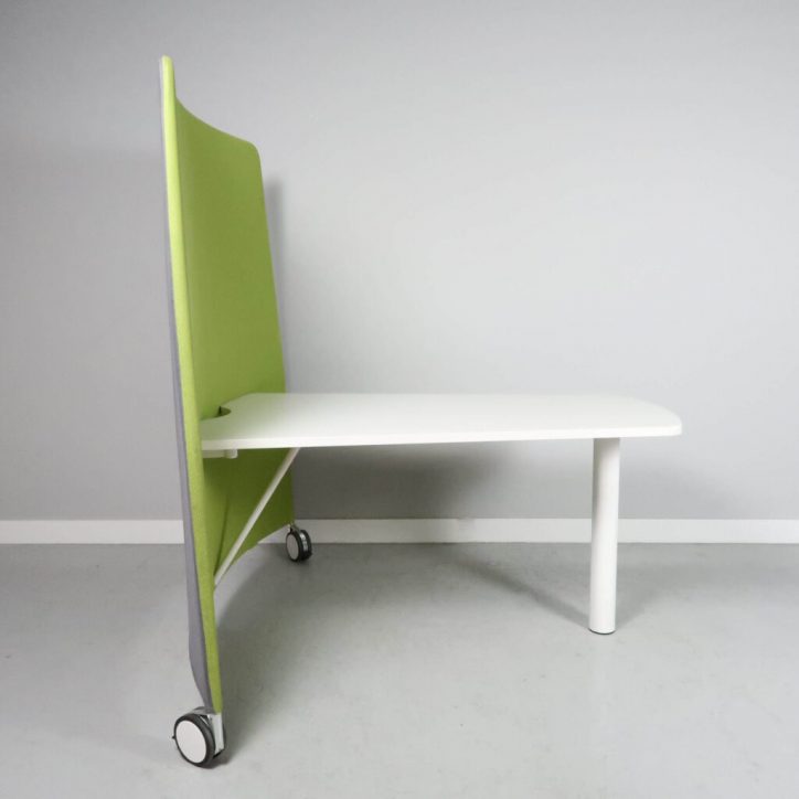 Begagnad arbetsstation Mobi från Abstracta. En golvskärm i grönt och grått på hjul med ett vit bord fäst vid sidan.