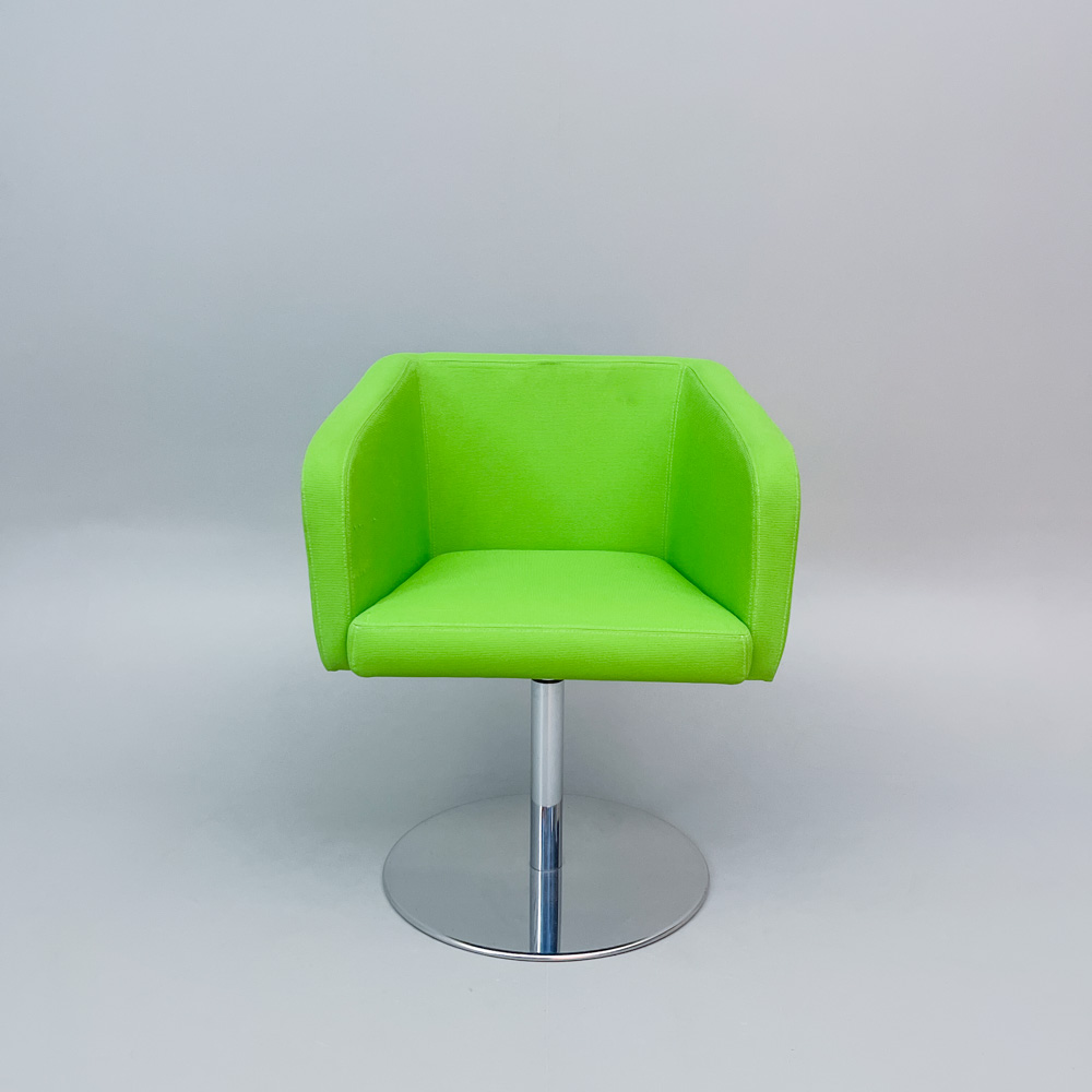 Grön fåtölj med modern design och metallfot mot ljus bakgrund.