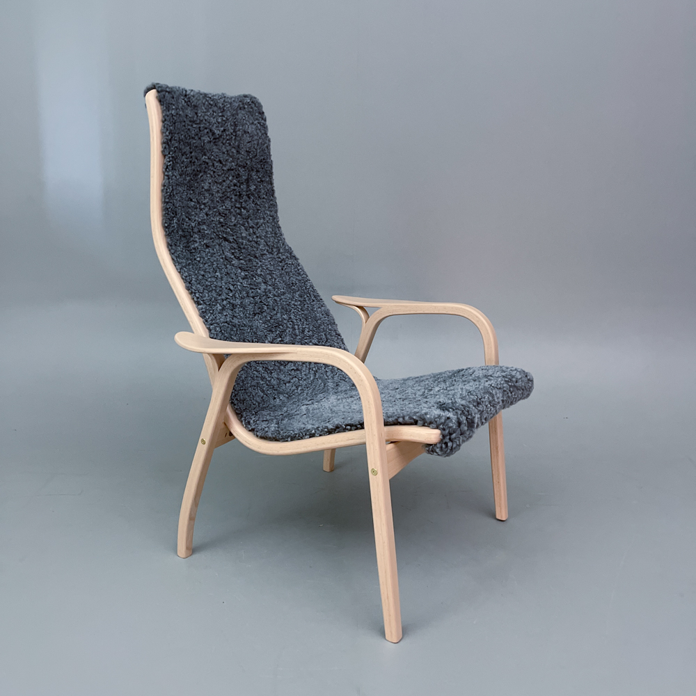 En fåtölj i ljust trä med en sits i fårskinn och hög rygg.