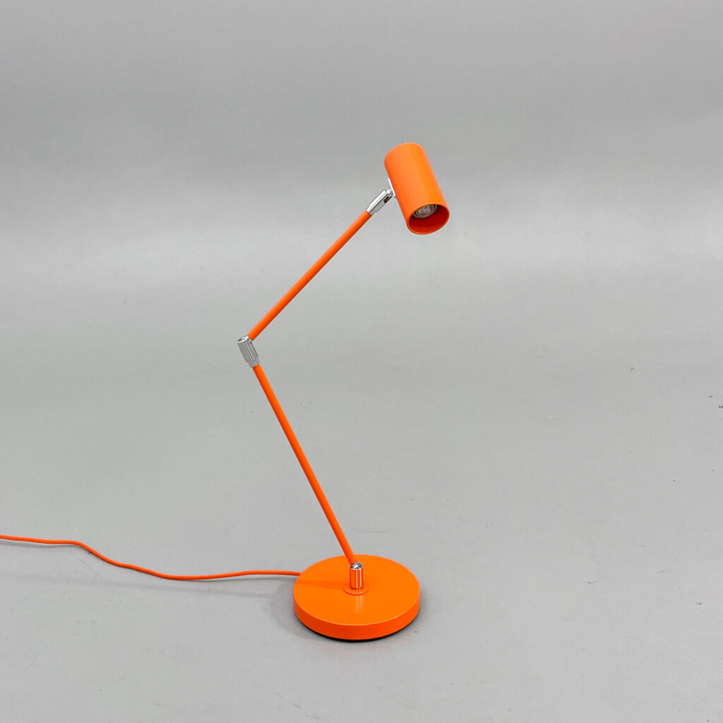 En smal orange skrivbordslampa med en ledad arm och en cylindrisk lampskärm.