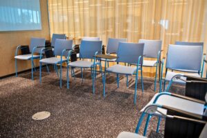 Mötesrum med stolar i rader, skrivplattor, whiteboard och gula gardiner