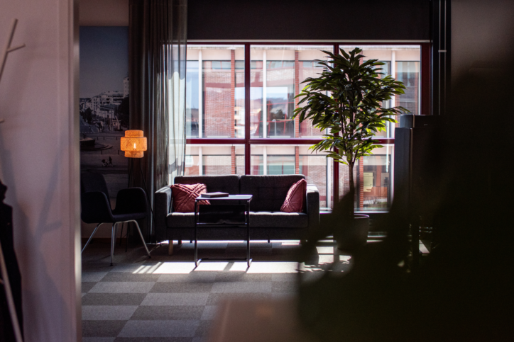 Soffhörna med röda kuddar, svart bord, växter, lampor och utsikt mot stad