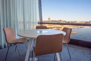 Runt bord med fyra stolar i rum med utsikt över stad, vatten och kyrktorn