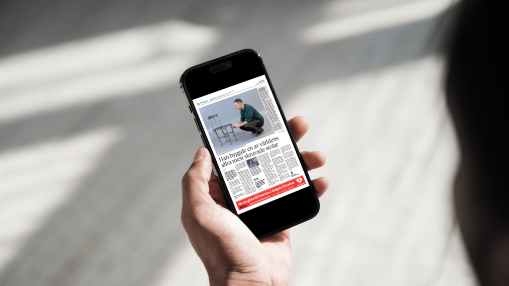 Person visar artikel om man som bygger stol av insexnycklar, på mobilskärm.