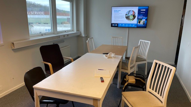 Rörigt konferensrum med olika typer av bord och stolar samt tv på väggen.