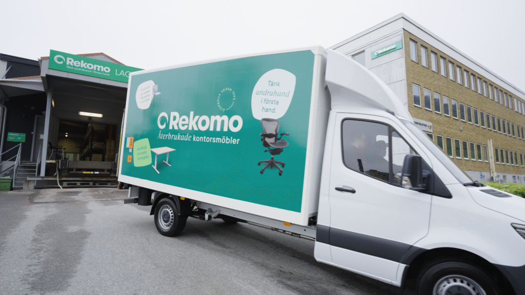 Rekomo-lastbil med reklam för återbrukade kontorsmöbler parkerad vid företagets byggnad.