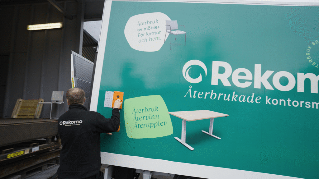 Person vid lastbil från Rekomo med logga och bilder på stol och bord.