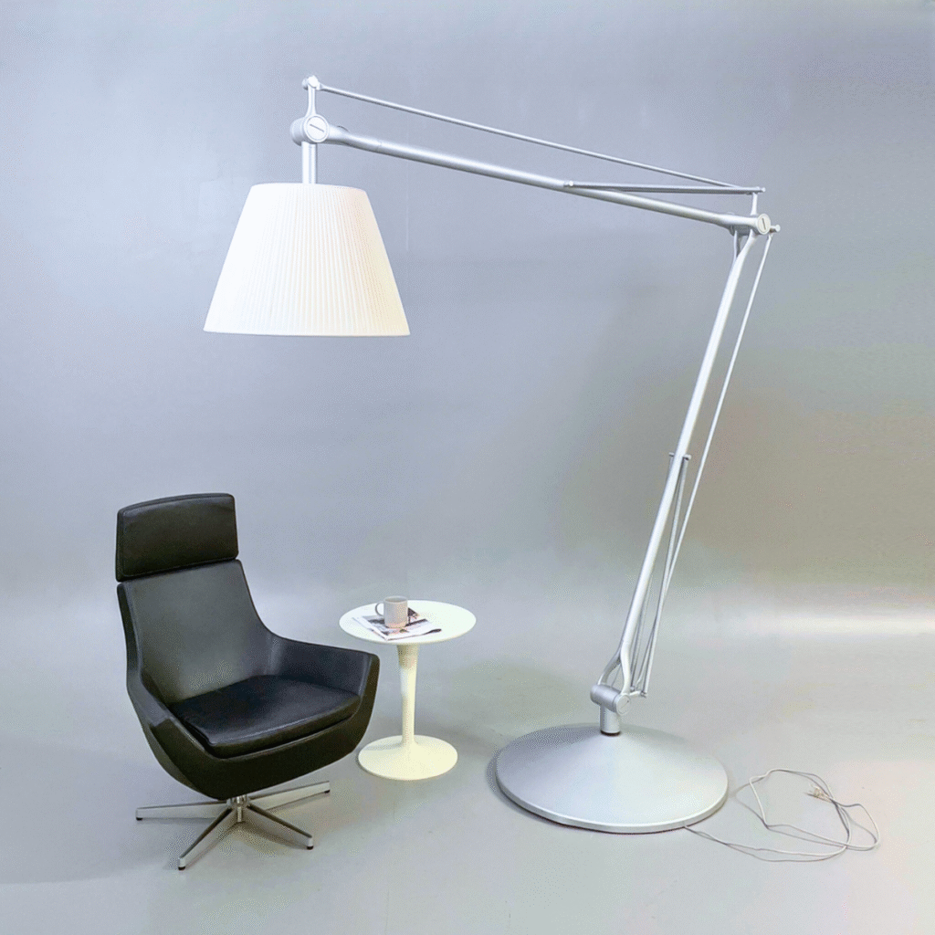 Flos SuperArchimoon golvlampa bredvid en svart fåtölj och ett vitt sidobord.