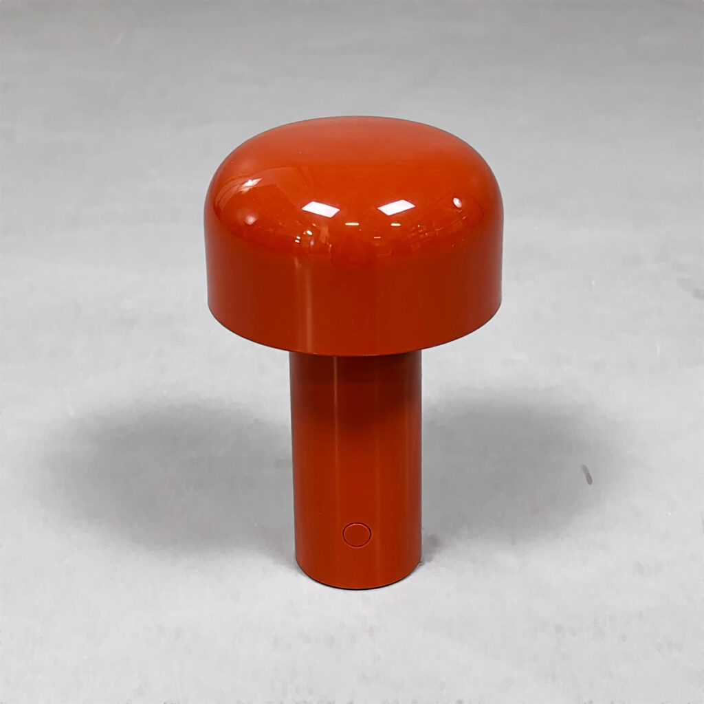 En orange bordslampa med en rund fot och en svampformad skärm.