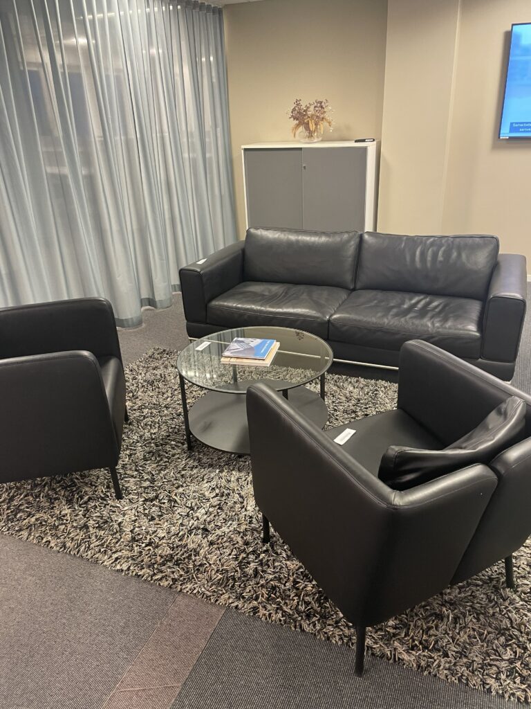 Loungegrupp med skinnmöbler och ett runt glasbord på en matta.