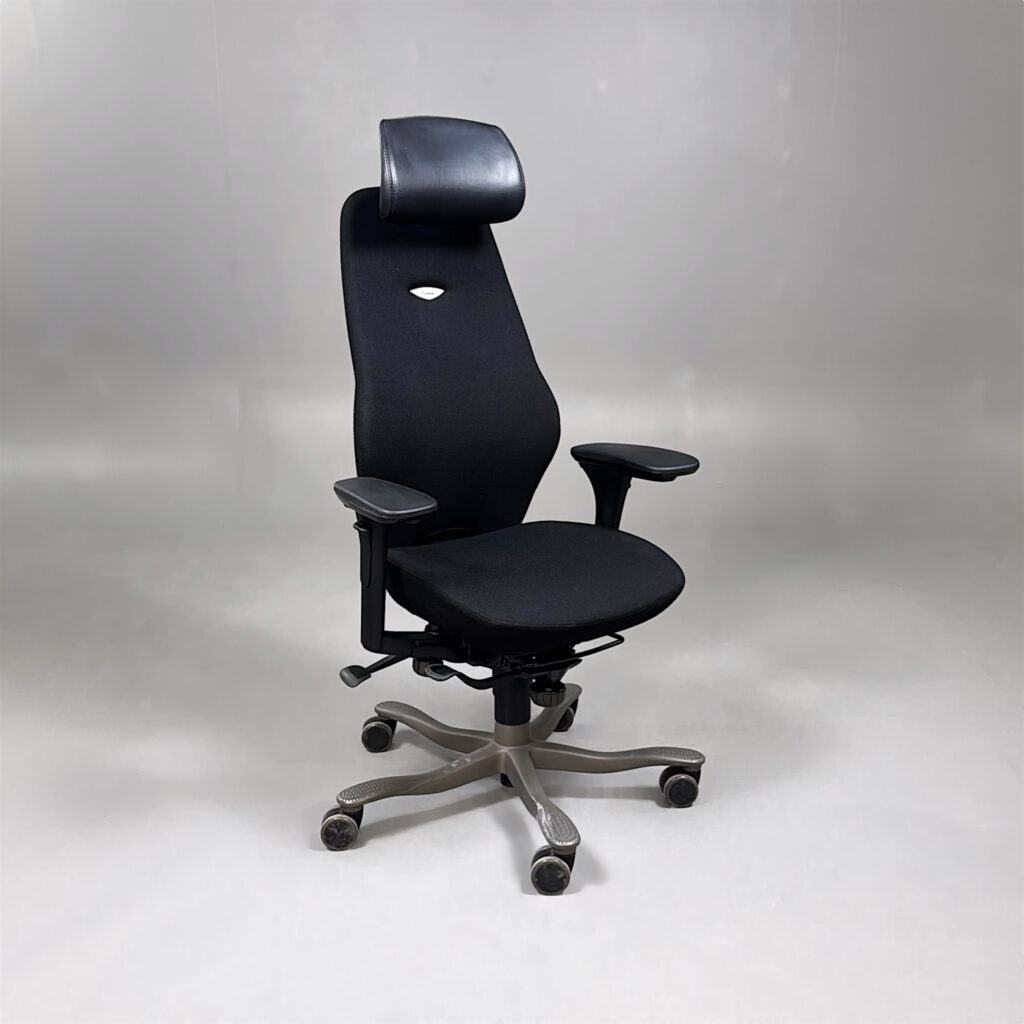 En svart ergonomisk kontorsstol med nackstöd och hjulförsett underrede.