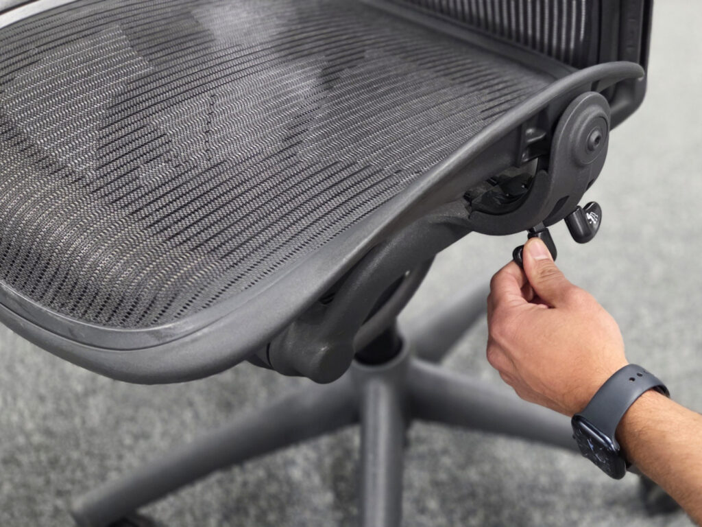 Närbild på en hand som justerar inställningarna på en Herman Miller Aeron kontorsstol.